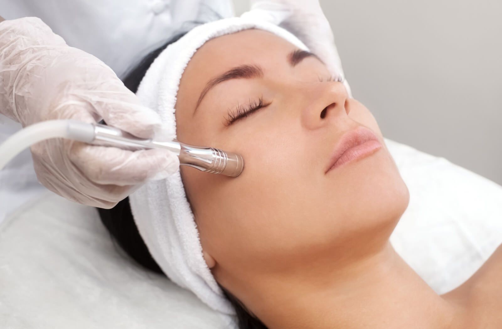 Esthetician performing a facial treatment with specialized equipment on a patient in a spa clinic.